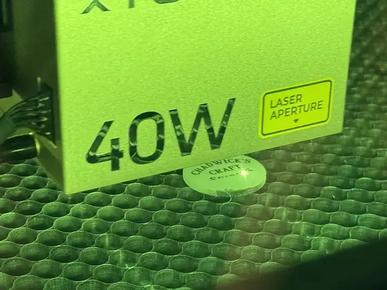 A laser engraving machine engraving "Chadwick's Crafts" onto a piece of wood.