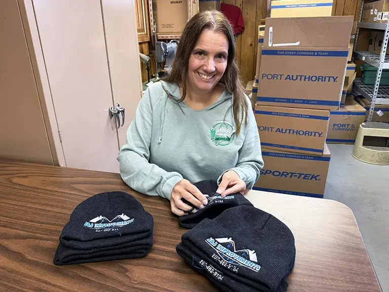 Jenny embroidering logos onto a beanie hat.
